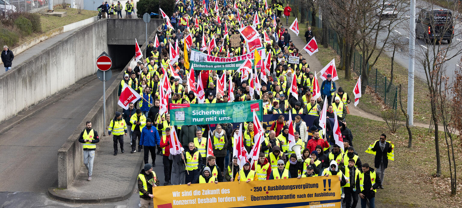 Ein Protestzug von Streikenden zieht mit Bannern und Verdi Fahnen zum Lufthansa Aviation Center.