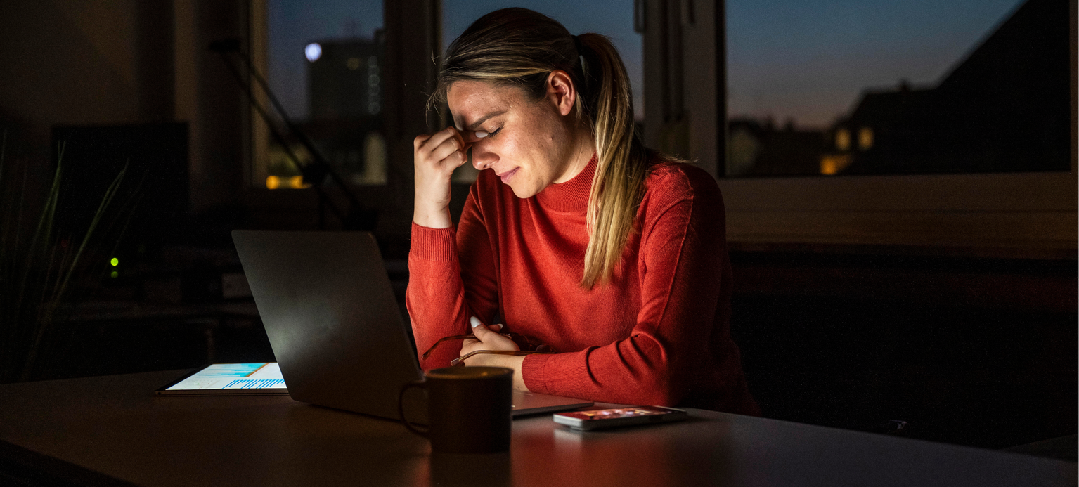 Stressed entrepreneur working late evening in dark office