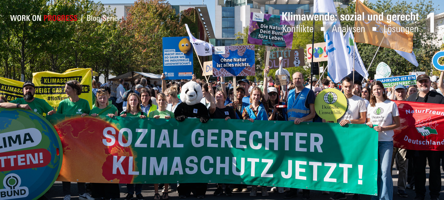 Demonstrant*innen zeigen ein Poster mit der Aufschrift Sozial gerechter Klimaschutz jetzt!  sowie weitere Plakate